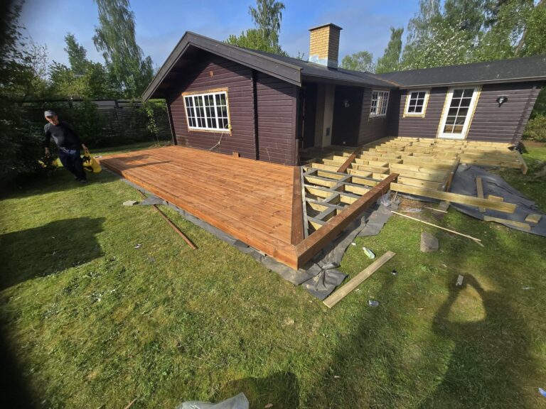 Træterrasse under opbygning ved mørkt træhus