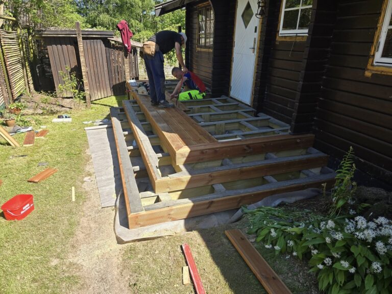 Personer bygger en træterrasse foran et hus