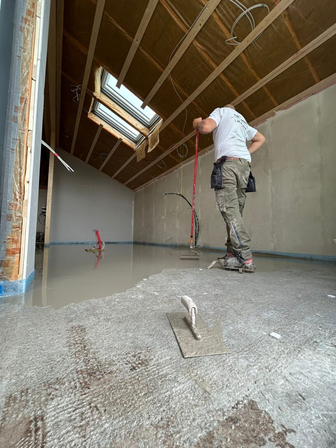 Håndværker udjævner nyt betongulv i loftsrum